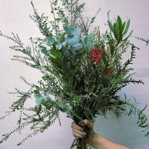 A large bouquet of flowers being held against a white wall