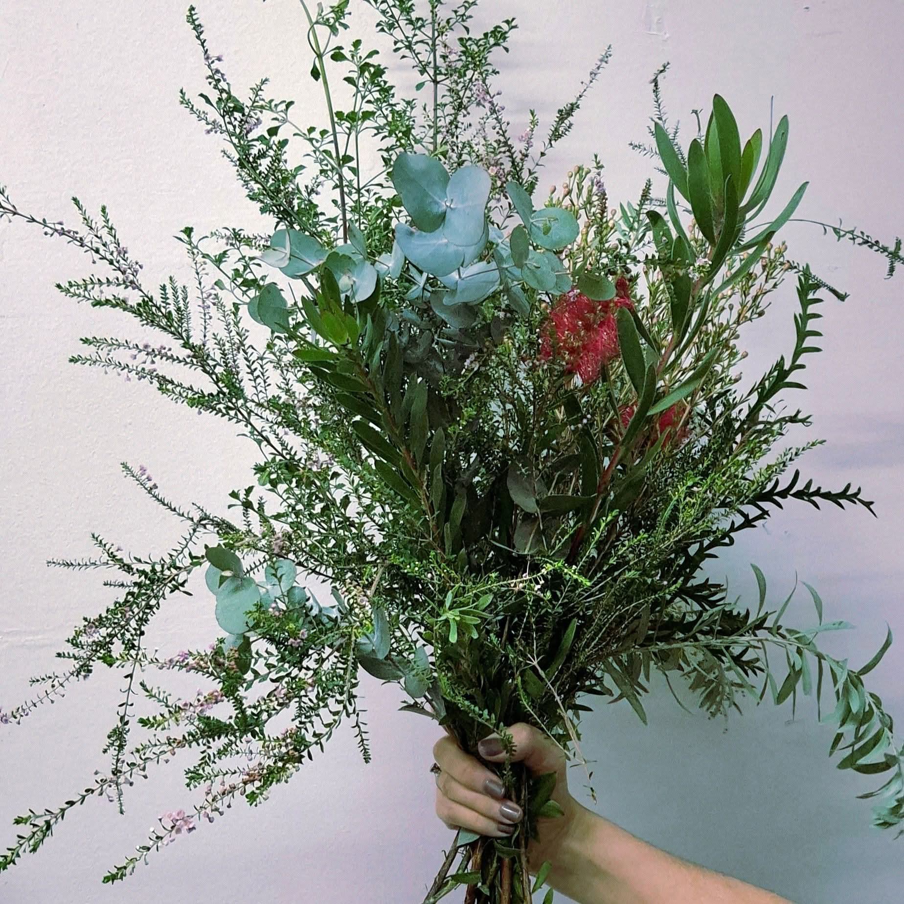 A large bouquet of flowers being held against a white wall